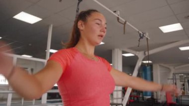 Pembe tişörtlü genç bayan dersten sonra spor kulübünde rahatlıyor.