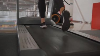 Genç bir kadın fitness kulübünde egzersiz yapıyor ve simülatörde kardiyo eğitimi alıyor.