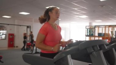 Pembe tişörtlü güzel bir genç kız vücut şeklini korumak için bir spor kulübünde nişanlanıyor.
