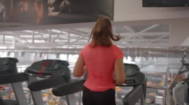 Büyük ve modaya uygun spor salonunu ziyaret edenler makinelerde kardiyo çalışmaları yapıyorlar.