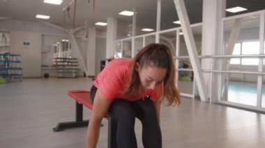 Kafasında at kuyruğu olan genç bir kadın büyük, modern bir spor kulübünde çalışıyor.