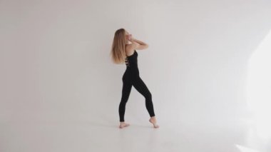 Stüdyoda çıplak ayakla esneme hareketleri yapan ince bir genç kız parmak uçlarında yükselir. Uyum ve denge kavramı