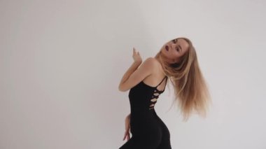 Güzel bir genç kız beyaz bir stüdyoda esniyor ve elleriyle düzgün hareketler yapıyor. Uyum ve denge kavramı