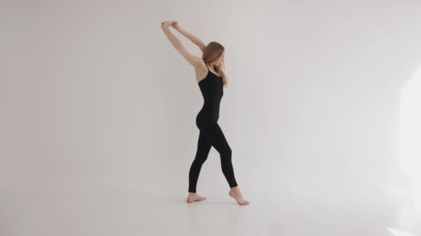 A young girl is engaged in stretching and stretches the muscles of the shoulder girdle by raising her arms and clasping them in a lock — Stock Video