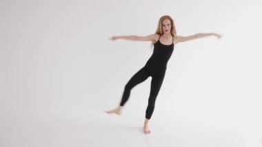 Muhteşem bir genç kız stüdyoda esneme hareketleri yapıyor ve bacağı yukarıda salıncak gibi sallanıyor.