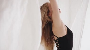 Stüdyoda ellerinde beyaz tül parçalarıyla dans hareketleri yapan şehvetli genç bir kız. Yavaş çekim