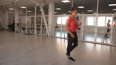 Güzel genç bir kız aynanın önünde salonun ortasında duruyor ve egzersizler arasında dinleniyor. Yavaş çekim