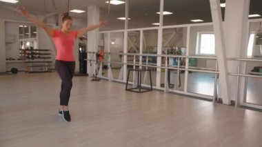 Spor salonunun ortasında elleri arkada duran pembe tişörtlü güzel bir kızın portresi. Yavaş çekim