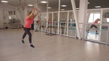 Enerjik genç bir kız jimnastik yapıyor düz kollarında takla atıyor yan takla atıyor ve spor salonunda sırtını çeviriyor. Yavaş çekim