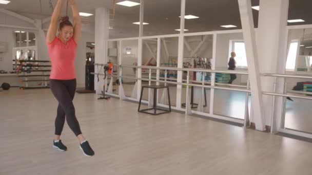 Молодая девушка делает гимнастические упражнения в тренажерном зале вперед сальто на прямых руках и смеется, не сохраняя равновесие. Медленное движение — стоковое видео