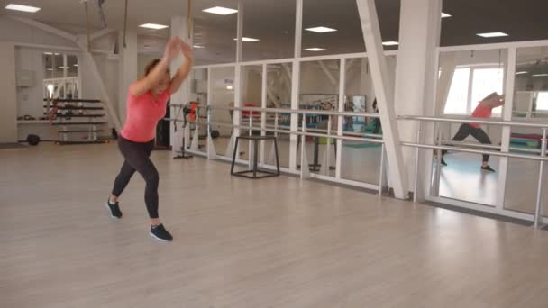 Enerjik genç bir kız jimnastik yapıyor düz kollarında takla atıyor yan takla atıyor ve spor salonunda sırtını çeviriyor. Yavaş çekim — Stok video