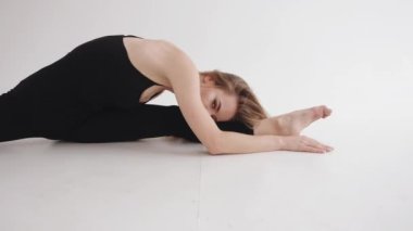 Stüdyoda güzel bir makyajı olan genç bir kız enine bir sicimin üzerine oturur ve belini güzelce büker.