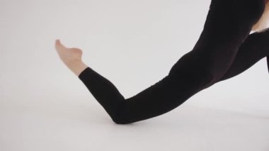 Stüdyoda uçan sarı saçlı güzel bir genç kız bacağının alt kısmıyla hamle yapıyor. Yan görünüm