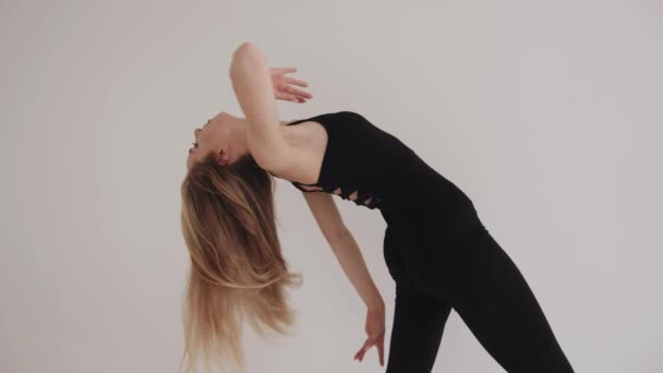 Een jong meisje met een heldere make-up in de studio is bezig met uitrekken met elementen van klassieke dans — Stockvideo