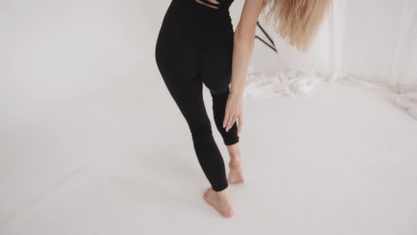 Bedårande ung flicka med långt blont hår gör stretching i studion och visar sensuella dansrörelser — Stockvideo