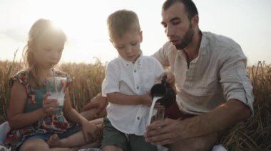Beyaz gömlekli küçük bir çocuk ablasının yanına oturur ve buğday tarlasında aile pikniğinde sütten süt döker. Yavaş çekim