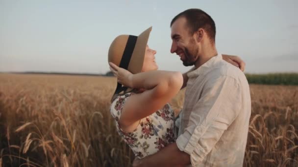 Um jovem casal está abraçando em um campo de trigo e beijos. Conceito de amor e felicidade. Movimento lento — Vídeo de Stock