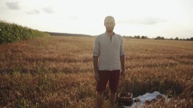 Beyaz gömlekli sakallı genç bir adam buğday tarlasından geçer. Yalnızlık ve yansıma konsepti. Yavaş çekim