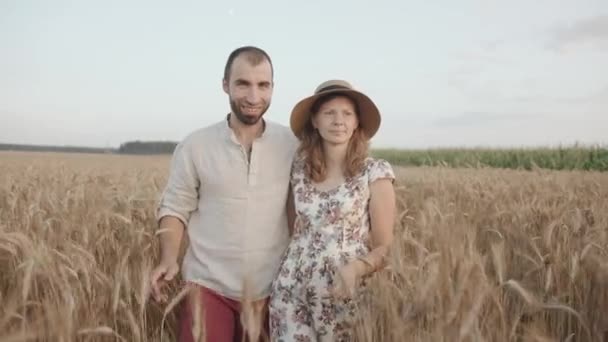 Un couple marié heureux profite d'une promenade en dehors de la ville et va embrasser dans un champ de blé. Mouvement lent — Video
