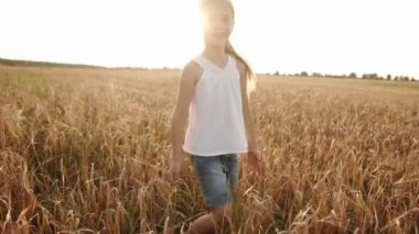 Buğday tarlasında beyaz ceketli uzun saçlı sarışın bir kızın portresi. Yavaş çekim