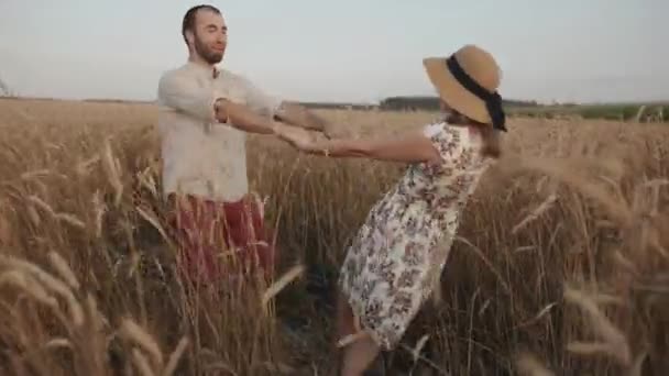Ένα χαρούμενο νεαρό παντρεμένο ζευγάρι στροβιλίζεται ανάμεσα σε ένα χωράφι με σιτάρι μια καλοκαιρινή μέρα. Έννοια αγάπης και ευτυχίας — Αρχείο Βίντεο