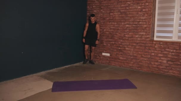 Junger muskulöser Mann steht im Raum und zeigt seinen großen Bizeps und zieht vor dem Training sein Hemd aus — Stockvideo