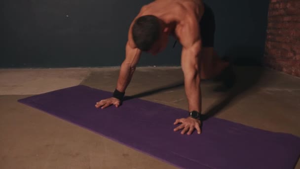Молодой культурист тренируется на коврике и делает подтягивания коленей к груди в доске — стоковое видео