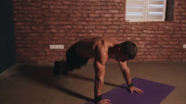 젊은 근육질의 남자가 장비 없이 방에서 운동하고 자신의 몸무게로 고밀도의 지방 연소 운동을 합니다 — 비디오