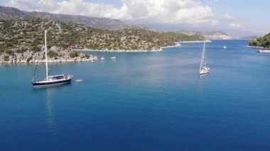 Suluada adasının volkanik körfezinin parlak mavi sularının ve turistlerle yelken açan yatların çarpıcı manzarası.