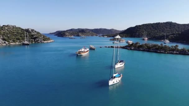 Luftaufnahme von Segelyachten und Kreuzfahrtschiffen im türkisfarbenen Wasser der Bucht und einer Reihe von baumbestandenen Berginseln — Stockvideo