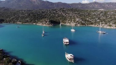 Saf mavi sularda yelkenli yatları ve Antalya 'da kayalık dağlarla Akdeniz kıyıları olan körfezin insansız hava aracı görüntüleri.