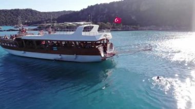 Türkiye, Kemer - 20 Ekim 2021: Yaz tatili sırasında dağlık bir adada turistlerle dolu büyük bir teknenin insansız hava aracı saldırısı