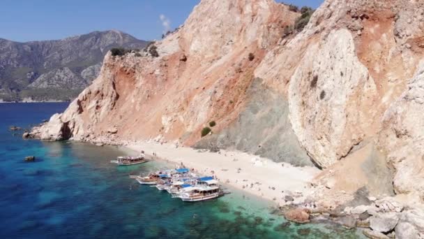 Drohnenaufnahmen der orangen Vulkanberge der Insel Suluada und des weißen Strandes mit Touristen und Yachten in der Bucht — Stockvideo