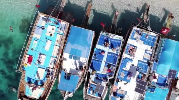 Vista dall'alto di una fila di yacht con turisti che prendono il sole sul ponte e sulla spiaggia dell'isola di Sualada nella baia mediterranea — Video Stock