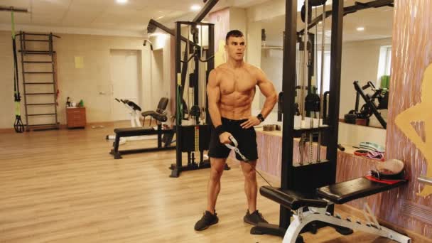 Młody mężczyzna trenuje na siłowni i podnosi proste ramię na symulatorze do pompowania mięśnia naramiennego — Wideo stockowe