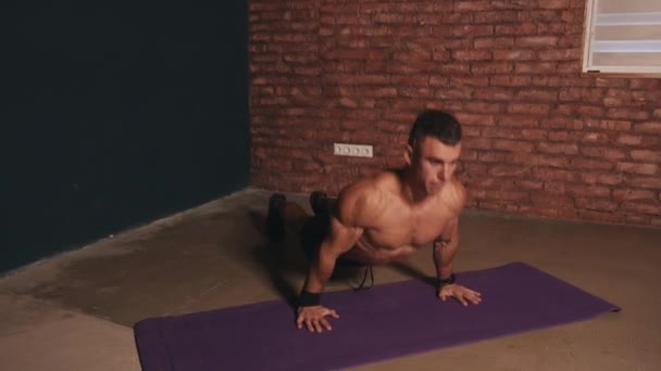 Молодой культурист тренируется на коврике и делает подтягивания коленей к груди в доске — стоковое видео