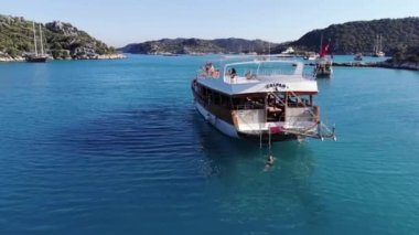 Türkiye, Kemer - 20 Ekim 2021: Yaz tatili sırasında dağlık bir adada turistlerle dolu büyük bir teknenin insansız hava aracı saldırısı