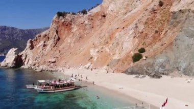 Suluada adasının volkanik kayaları ve körfezdeki yatlarla çevrili kumlu bir sahilde turistlerin insansız hava araçlarıyla vurulması.