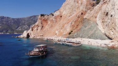 Suluada adasının volkanik kayaları ve körfezdeki yatlarla çevrili kumlu bir sahilde turistlerin insansız hava araçlarıyla vurulması.