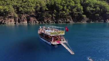 Türkiye, Kemer - 20 Ekim 2021: Koyun mavi sularında turistlerle yatların ve güneşli bir yaz gününde ağaçlarla kaplanmış kayalık adaların insansız hava araçlarıyla vurulması