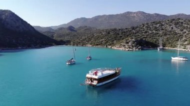 Suluada adasının volkanik körfezinin parlak mavi sularının ve turistlerle yelken açan yatların çarpıcı manzarası.
