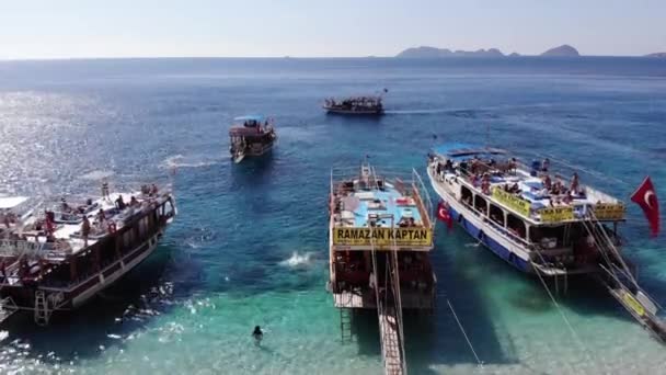 Türkei, Kemer - 20. Oktober 2021: Luftaufnahme von Touristen am weißen Sandstrand der Insel Suluada und vielen Yachten im türkisfarbenen Meer in Küstennähe — Stockvideo