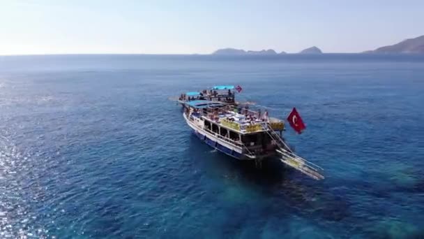 Türkiye, Kemer - 20 Ekim 2021: Akdeniz 'in berrak sularında güneşten parlayan güvertede turistlerle dolu yatların havadan görüntüsü — Stok video