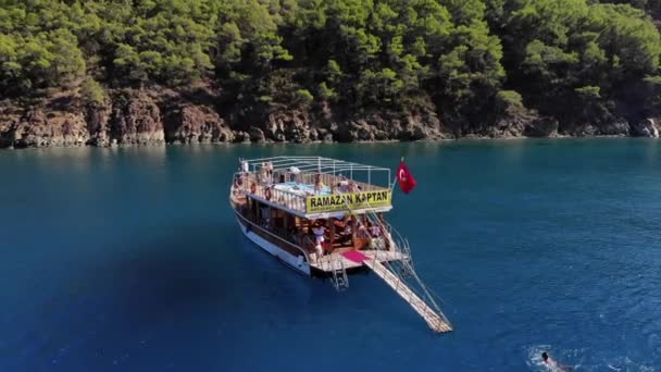 Türkei, Kemer - 20. Oktober 2021: Drohnenabschuss von Yachten mit Touristen im blauen Wasser der Bucht und der mit Bäumen bewachsenen Felseninseln an einem sonnigen Sommertag — Stockvideo