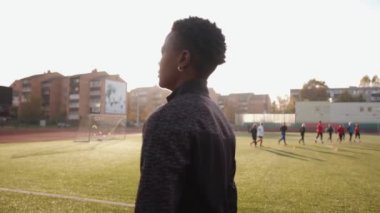 Neşeli genç bir Afrikalı Amerikalı kadın stadyumun koşu bandına çıkar ve gülümser. Yavaş çekim