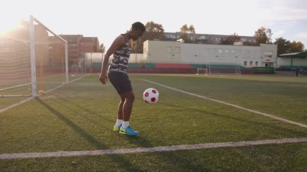 활동적 인 한 젊은 흑인 소녀 가 경기장에서 훈련을 받으면서 축구 공을 그 골의 배경 과겨루고 있다. 느린 동작 — 비디오