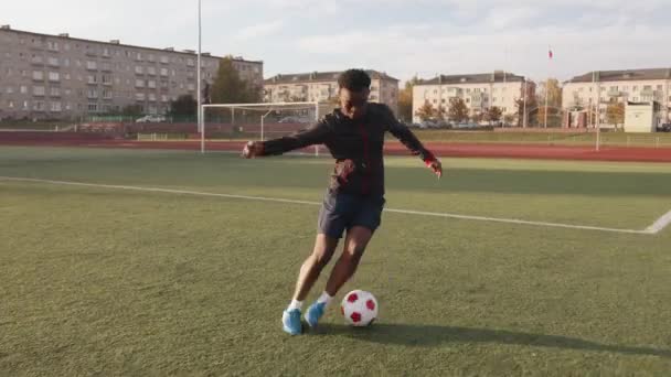 Genç siyahi kız stadyumda antrenman yapıyor ve top taşıma tekniği üzerinde çalışıyor. — Stok video