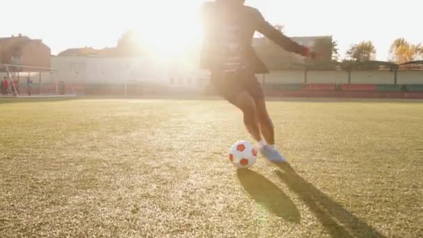 Stadyumda futbol antrenmanında genç ve enerjik bir zenci kız top kontrolü egzersizleri yapıyor ve ustalıkla tekme atmayı başarıyor. — Stok video