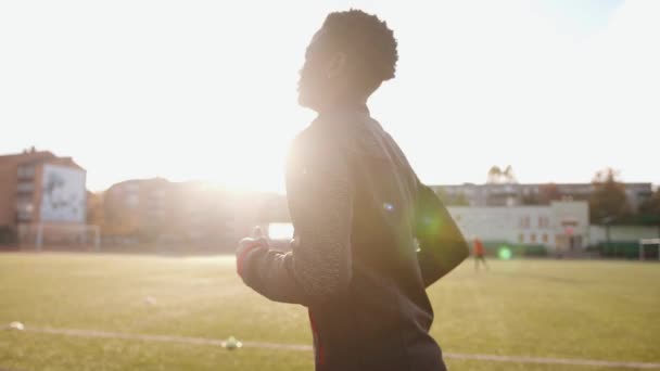 Uma jovem negra de uniforme esportivo corre na esteira do estádio da cidade. Vista traseira. Movimento lento — Vídeo de Stock