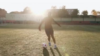 Futbol antrenmanındaki genç siyah kız hareket halinde top tutuşu egzersizi yapıyor ve taktik manevralar yapıyor.